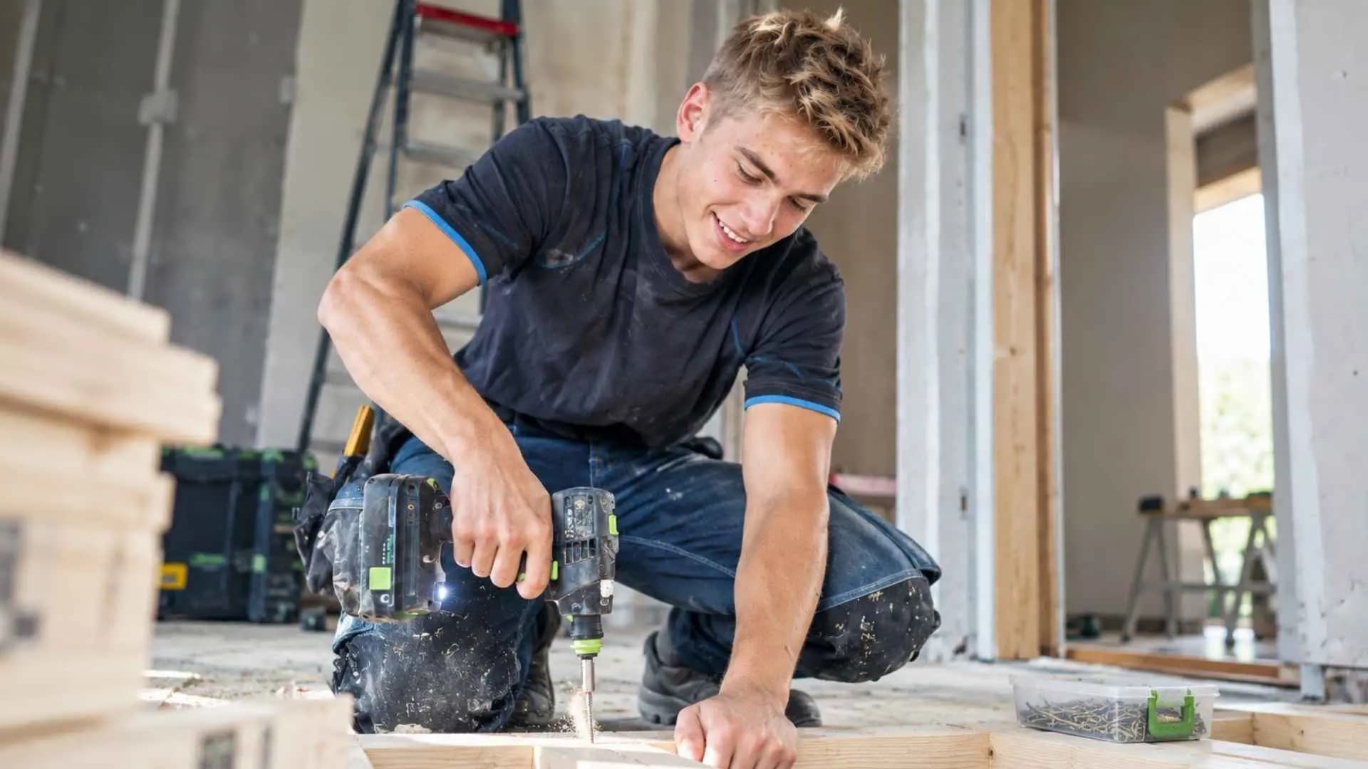 Timmerman schroeft een houten regelwerk vast op de bouwplaats.