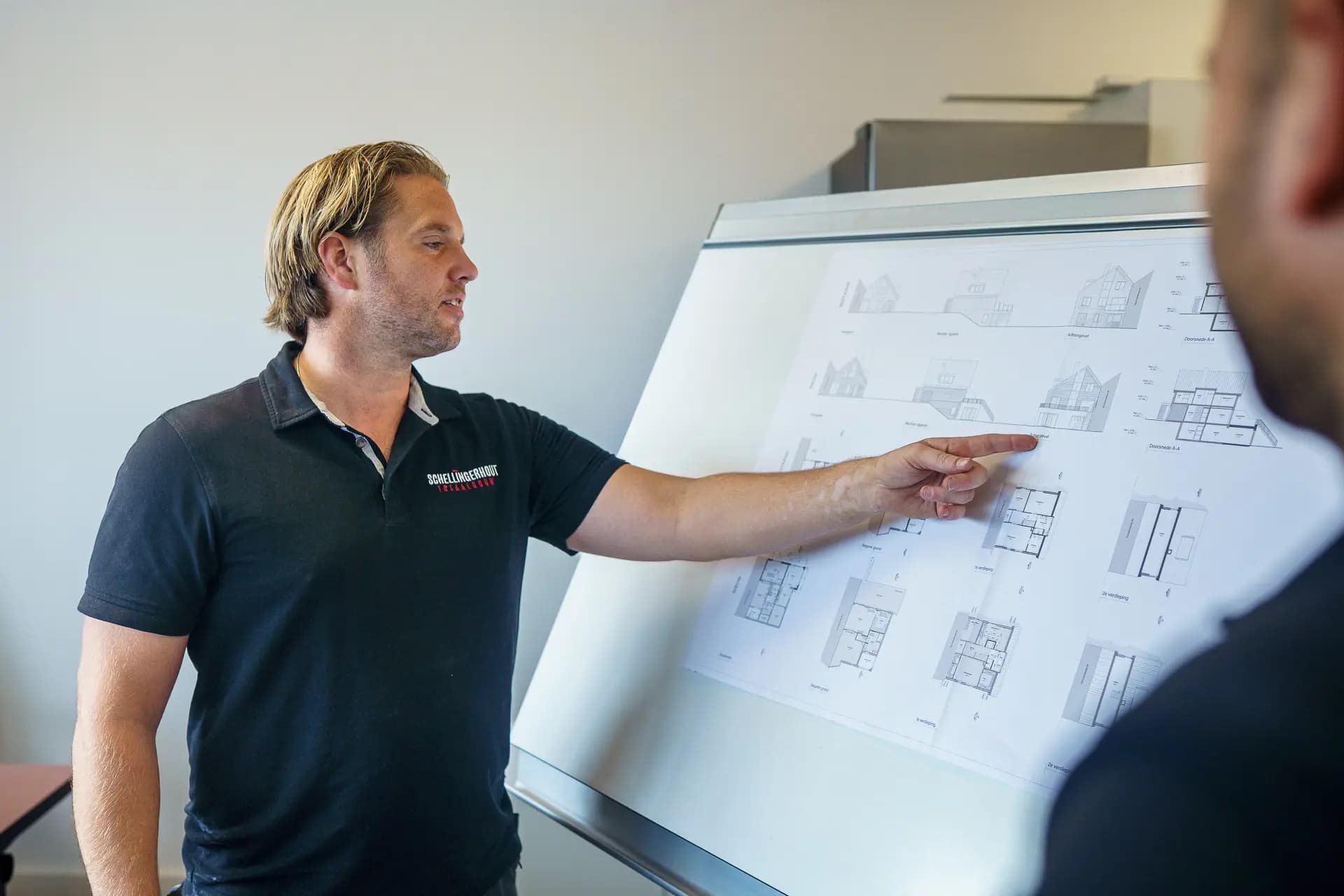 Werkvoorbereider van Schellingerhout licht bouwtekeningen toe aan een collega.